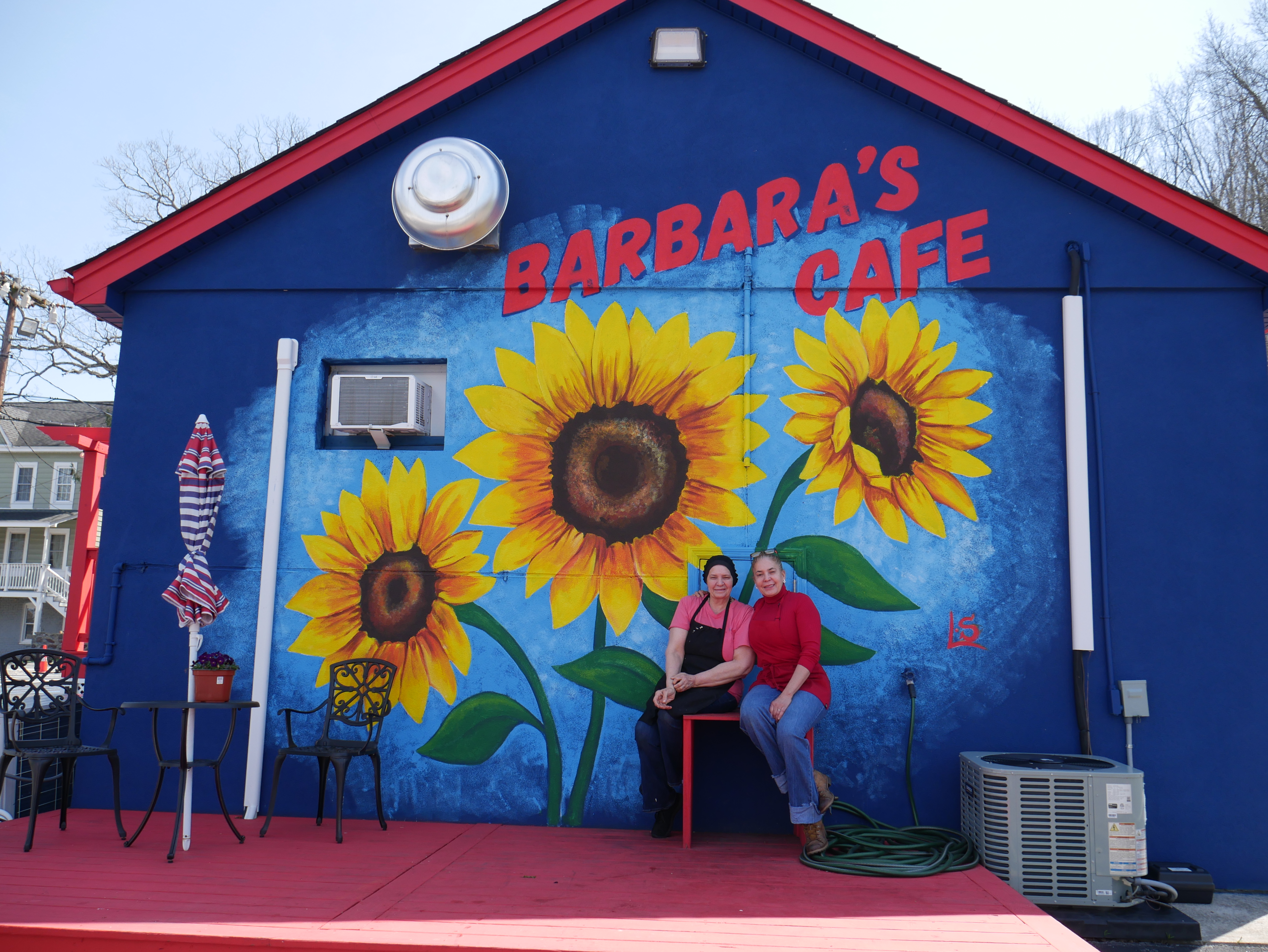 Barbara's Cafe family portrait beside the cafe mural